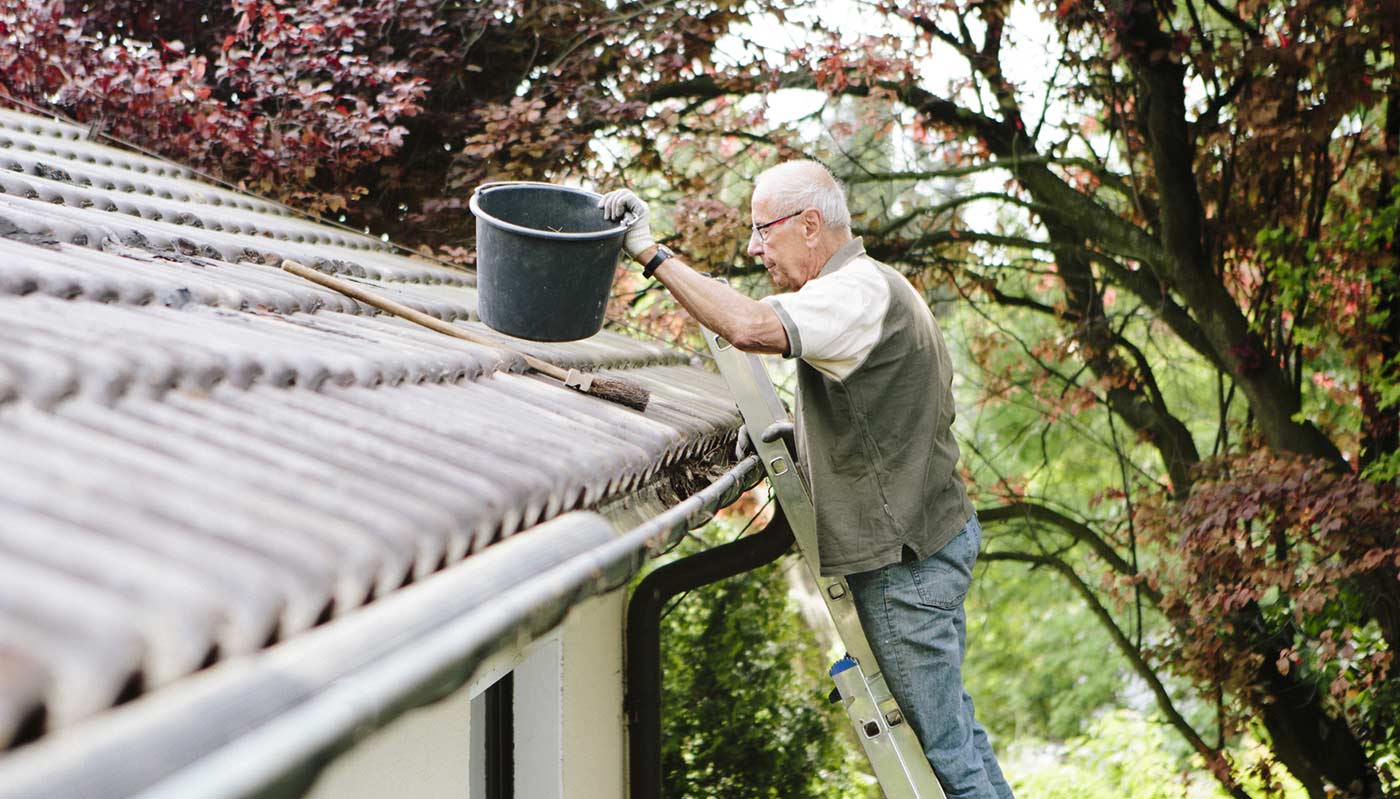 Man on ladder cleaning gutters