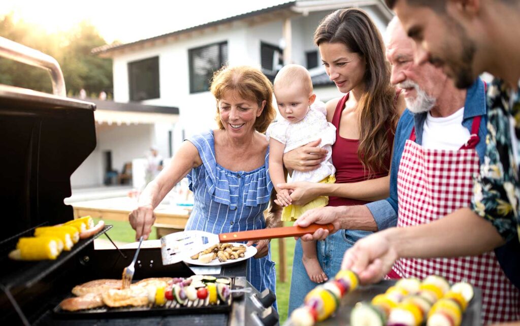 Family grilling food at an outdoor summer party